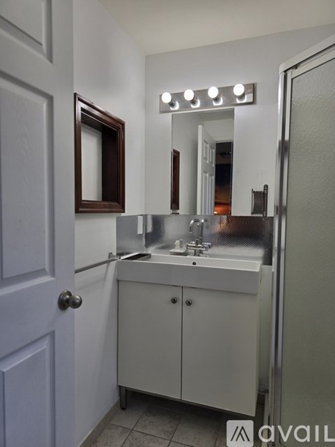 A bathroom with a white sink and a mirror with lights above it.