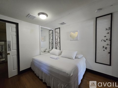 A bedroom with a white bed and a heart-shaped light on the wall.