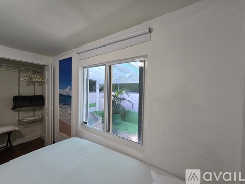 A bedroom with a large bed and a window overlooking a backyard.