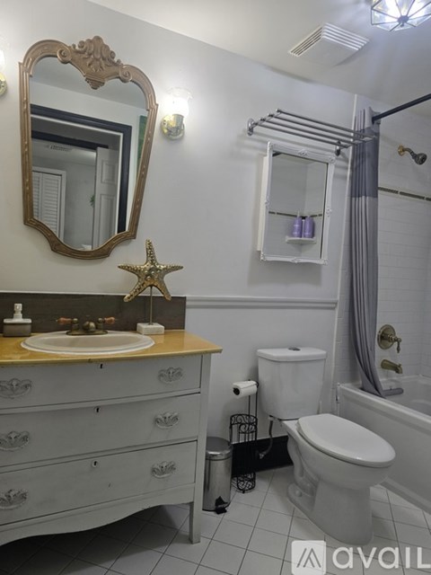 A bathroom with a toilet, sink, and mirror.