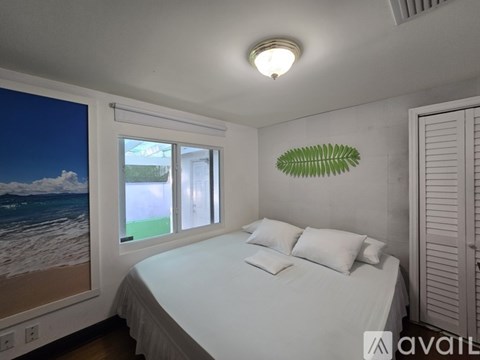 A bedroom with a large bed and a picture of the beach on the wall.