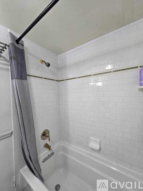 A bathroom with a white tub and a grey shower curtain.