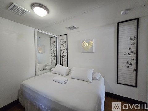 A bedroom with a white bed and a mirror on the wall.