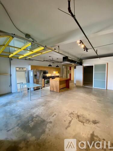 A large empty room with a kitchen area in the background.