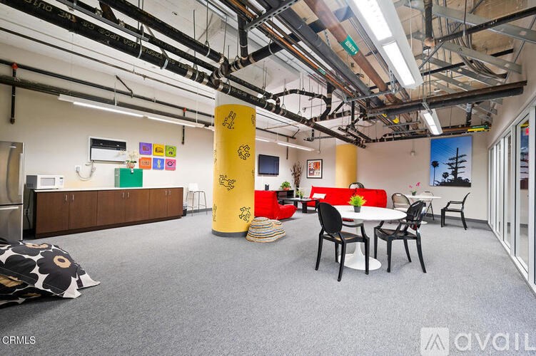 A room with a white table surrounded by black chairs.