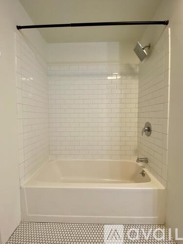 A white tiled bathroom with a bathtub and shower.
