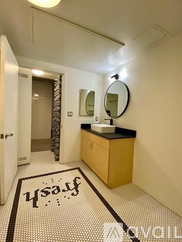 A bathroom with a sink, mirror, and a rug that says "Hello".