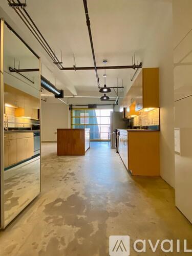 A large, empty kitchen with a long counter and a refrigerator on the left side.