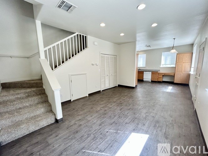 A spacious room with wooden flooring and a staircase with a beige carpet.