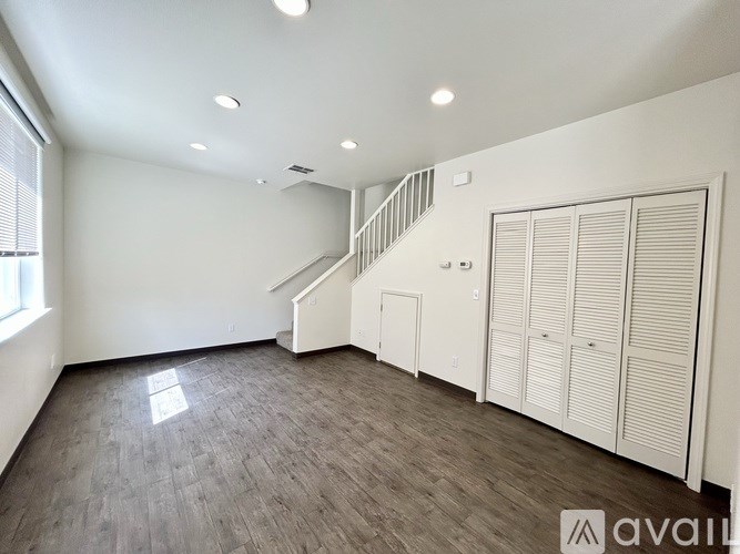 A spacious room with a staircase and wooden flooring.