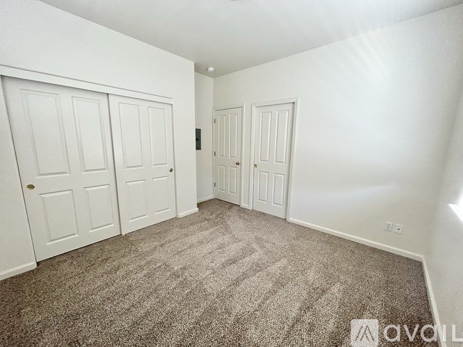 A carpeted room with three doors and one window.