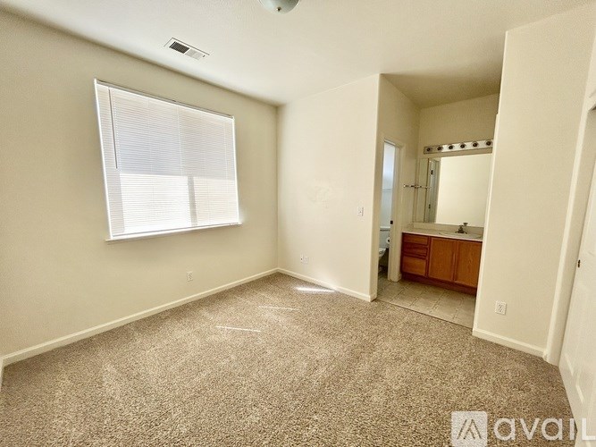A carpeted room with a window and a door leading to another room.