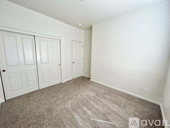 A carpeted room with three doors and no furniture.