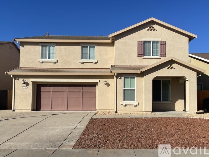 A beige house with a brown garage door and a brown roof.