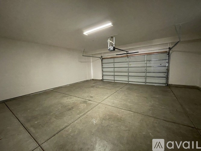 A large, empty room with a garage door on the back wall.