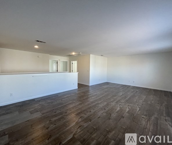 A spacious room with wooden flooring and white walls.