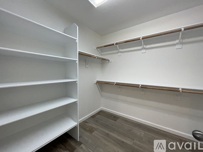 A walk-in closet with white shelving and wooden shelves.