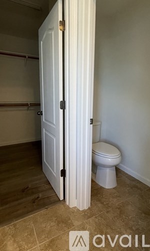 A white door is open to a bathroom with a toilet.
