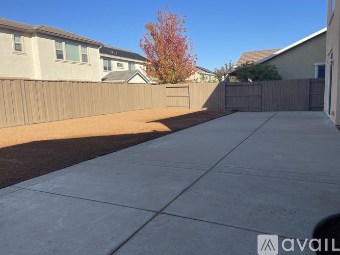 A backyard with a concrete path and a brown fence.