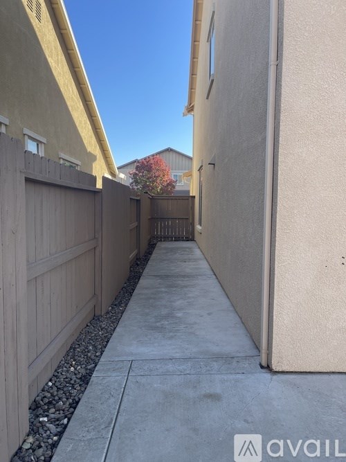 A narrow alley with a sidewalk and a fence on the left.