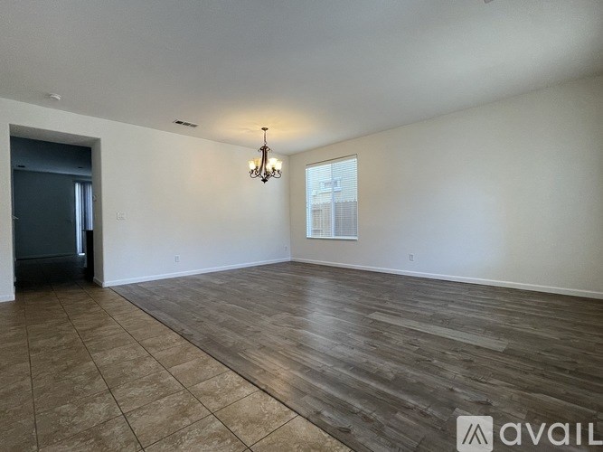 A spacious room with wooden flooring and a chandelier hanging from the ceiling.