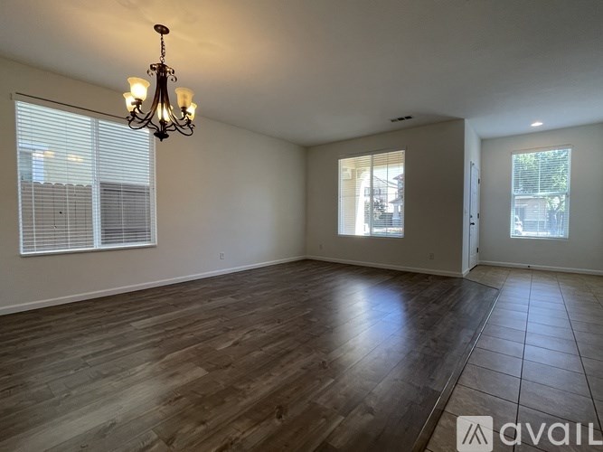 A room with wooden floors and a chandelier hanging from the ceiling.