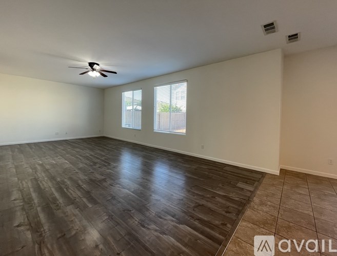 A spacious room with wood flooring and a ceiling fan.