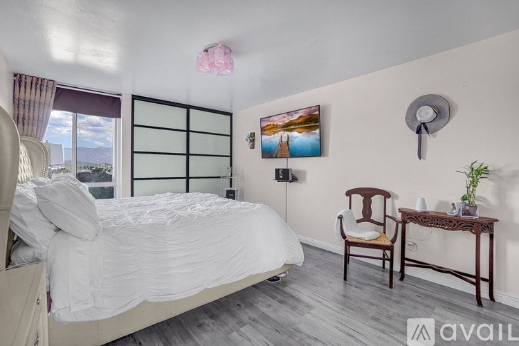 A bedroom with a large bed, a chair, and a table with a plant on it.