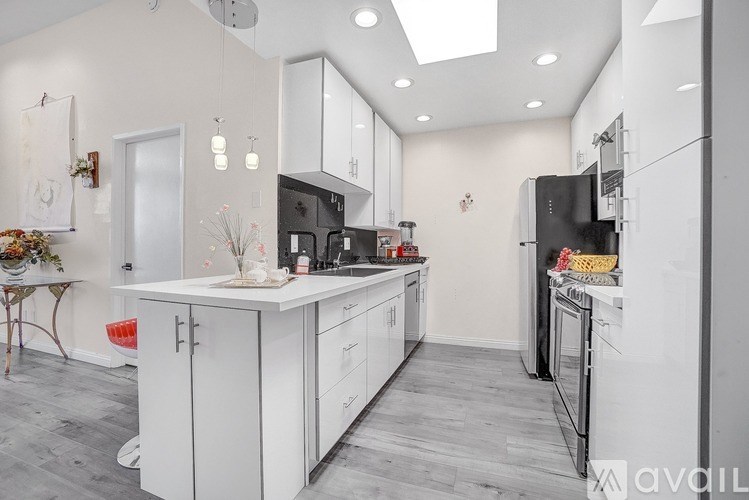 A modern kitchen with white cabinets and a black fridge.