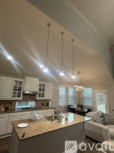 A kitchen with granite countertops and pendant lights.