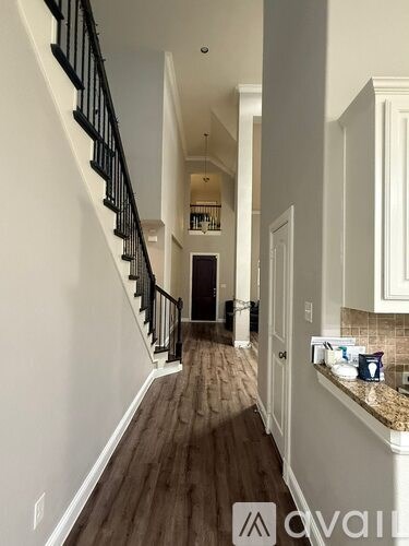 A hallway with a staircase and a counter with a sink.