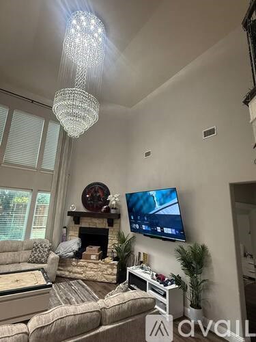 A living room with a couch, a television, a fireplace, and a chandelier.