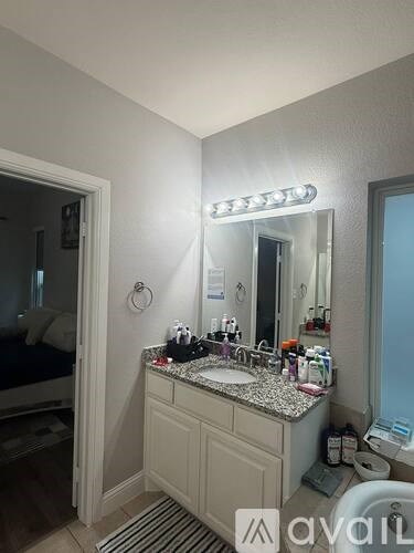 A bathroom with a sink, mirror, and a lit up light above the mirror.