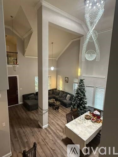 A living room with a Christmas tree and a chandelier.