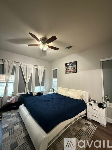 A bedroom with a bed, nightstands, and a ceiling fan.