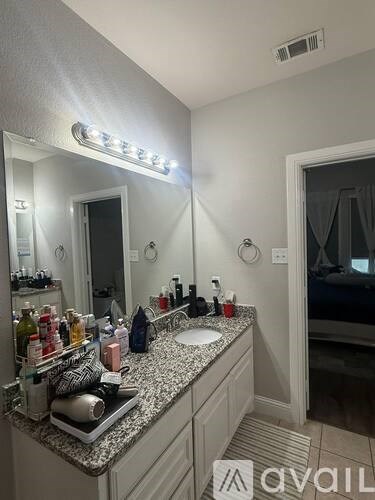 A bathroom with a vanity, a mirror, and a light strip above it.