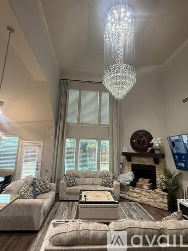 A living room with a grey sofa, a chandelier, and a fireplace.