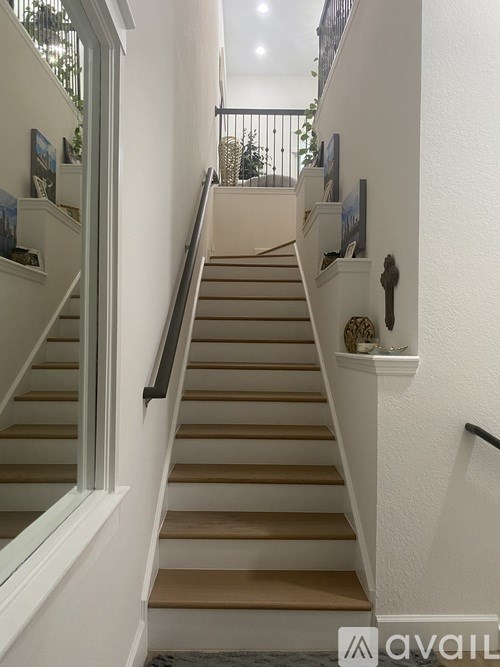 A staircase with a white wall and a black railing.