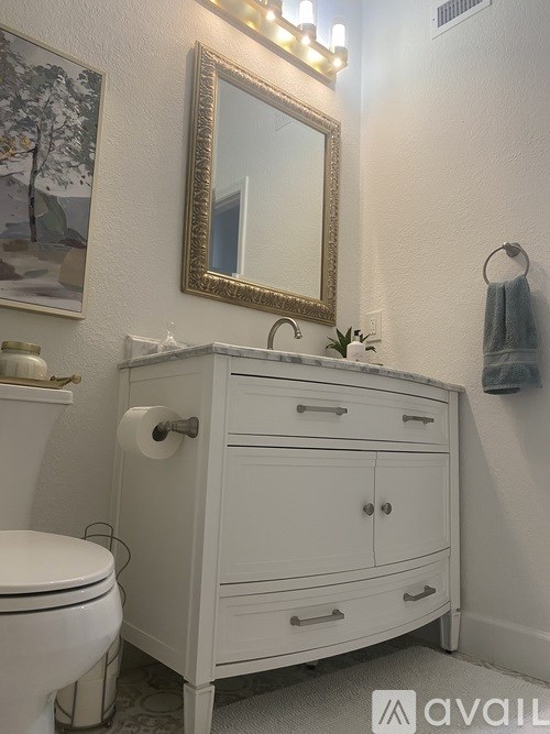 A white bathroom with a toilet, sink, and mirror.