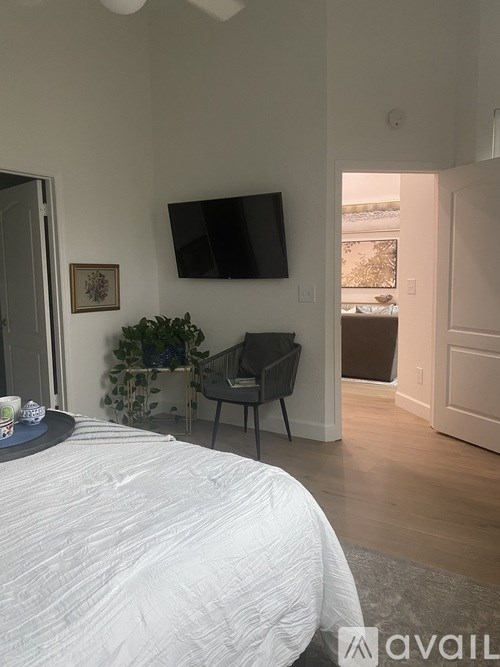 A bedroom with a bed, chair, and a television mounted on the wall.