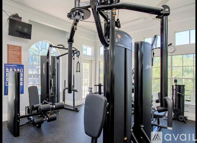 A gym with a variety of equipment including a squat rack, leg press machine, and a flat bench.