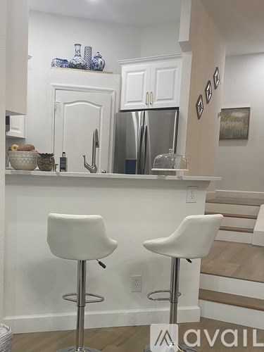 Two white bar stools are in front of a white counter.