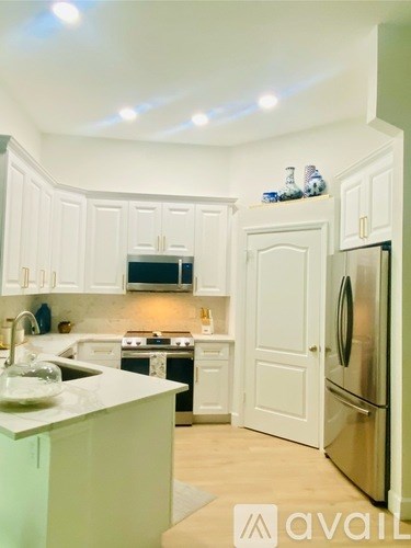 A kitchen with white cabinets and a stainless steel refrigerator.