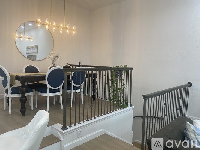 A dining area with a round mirror and a chandelier.