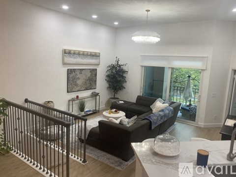 A living room with a black couch and a glass table.