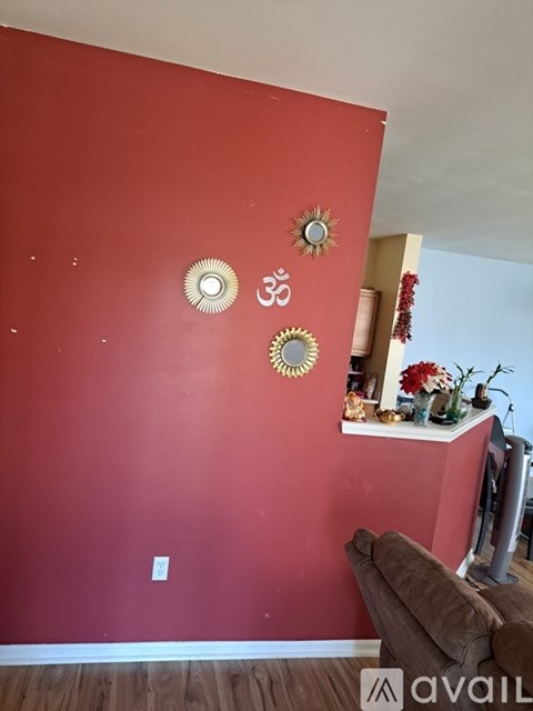 A living room with a red wall and a brown couch.