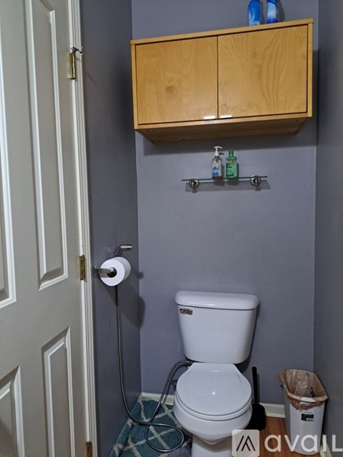 A white toilet in a bathroom with a wooden cabinet above it.