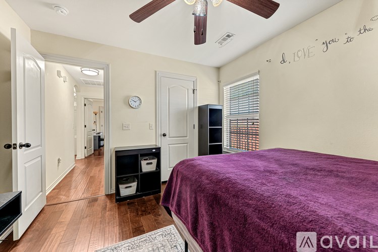 A bedroom with a purple bedspread and a ceiling fan.