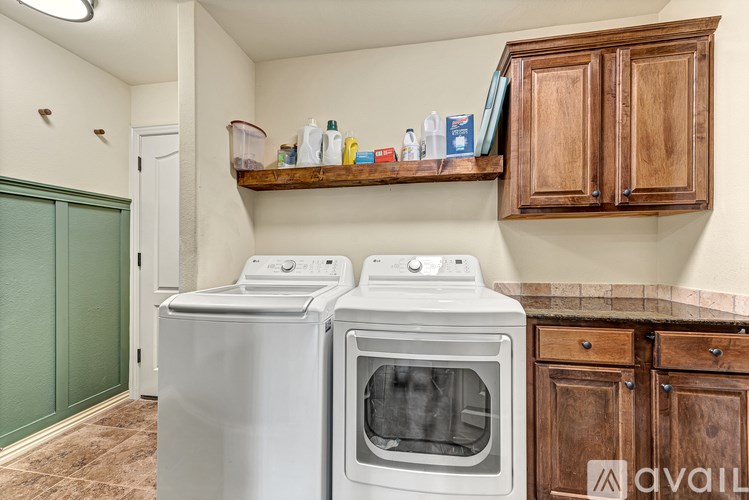 A white dishwasher and oven sit next to a wooden cabinet in a kitchen.