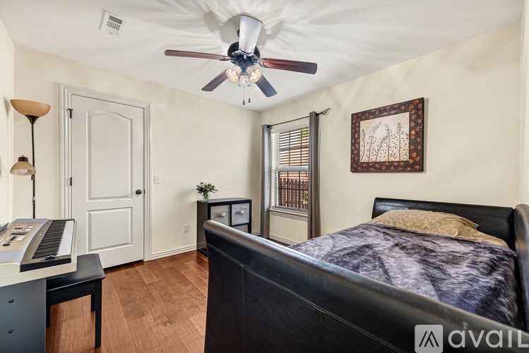 A bedroom with a bed, a desk, and a ceiling fan.
